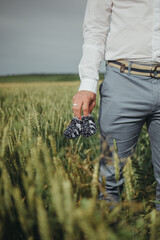 groom in the field with baby shoes