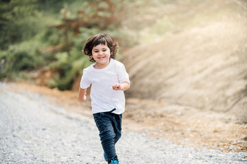 boy running to the camera through a forest