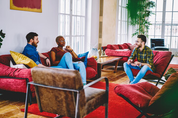 Cheerful group of multiracial friends having fun during free time in modern loft interior...