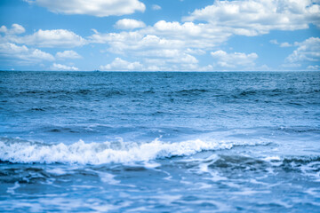 Shallow depth of field shot of Sea water Blurred white wave bubble images and a blue sky with white clouds.at Chanthaburi Coast, Thailand.soft focus.