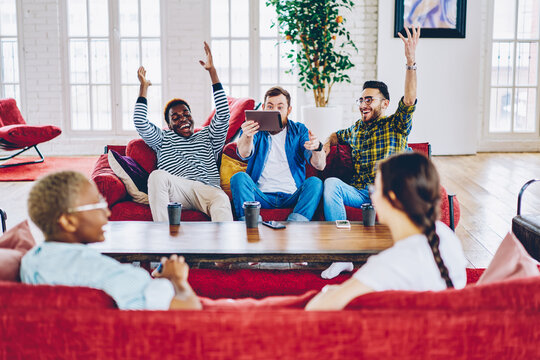 Overjoyed millenial men celebrating of passing next level in new video game on digital tablet,excited emotional hipster guys happy about victory in online contest  spending time in modern coworking .