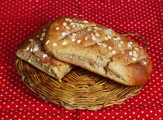 Loaves of whole wheat bread sprinkled with rolled oats on a wicker tray