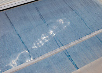 Dew drops on glass in front of water.
