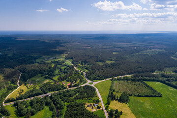 Aerial view of cloudy sunny day. Countryside surrounded by green fields, rivers and trees.