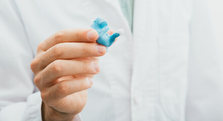 Doctor holding in his hands molded individual hearing aid earmolds for his patient, close-up....
