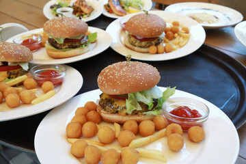 Plates with burgers and potatoes on tray