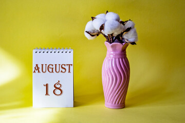Calendar with text 18 august on yellow background and with a vase of flowers