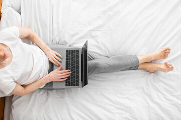 Naklejka premium Successful woman sitting in bed working on laptop