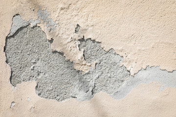 Exterior facade wall peeling plaster, outdoor natural sunlight light. Cement wall surface painted with beige color damaged and peeled background.