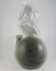 Whale money box with plastic waste symbolizing pollution of environment and of the oceans isolated on white background