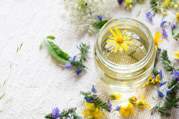 Close-up of fresh honey in glass jar with wild flowers and light textile in background