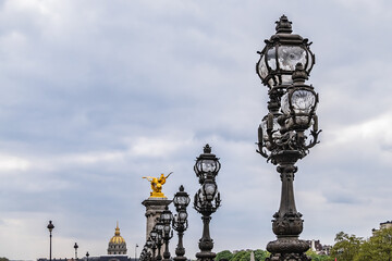 Fototapeta na wymiar Art Nouveau lamps on famous Alexandre III Bridge in Paris. Alexandre III Bridge, with exuberant, cherubs, nymphs and winged horses at either end, was built in 1896 - 1900. Paris, France.