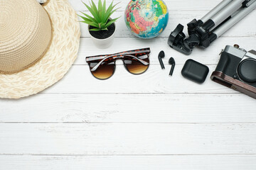 Flat lay vacation planing and traveling on  holiday concept on white wooden table background with earphone and sunglasses, straw hat and green plant,  camera and Tripod, Top view with copy space