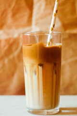 Dalgona coffee in glass with paper straw banner. Trending drink on paper background. Cold cocktail. Whipped coffee cream