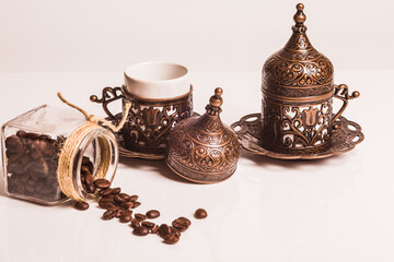 Two coffee cups with saucers made of copper and porcelain in a oriental style stand on a plastic white background. 