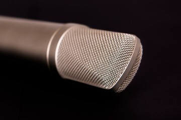 Closeup of a silver Condenser microphone under the lights isolated on a black background - Powered by Adobe