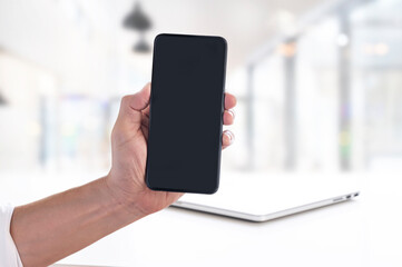 Man and blank screen mobile phone over blurred background.
