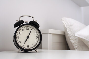Wake up concept. Close up view of alarm-clock in morning bedroom environment. An image of a retro clock showing 07:05 am. 