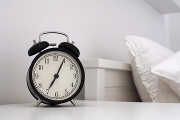 Wake up concept. Close up view of alarm-clock in morning bedroom environment. An image of a retro...