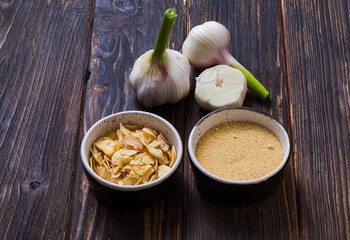 Fresh, dried and ground garlic on wooden surface
