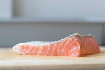 Salmon slices resting on a wooden chopping board.