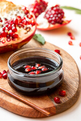 Narsharab (Azerbaijani: Narşərab) -Azerbaijani pomegranate sauce in a glass bowl closeup and fresh pomegranate. Fruit sauce for meat, oriental cuisine.