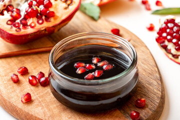 Narsharab (Azerbaijani: Narşərab) -Azerbaijani pomegranate sauce in a glass bowl closeup and fresh pomegranate. Fruit sauce for meat, oriental cuisine.