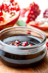 Narsharab (Azerbaijani: Narşərab) -Azerbaijani pomegranate sauce in a glass bowl closeup and fresh pomegranate. Fruit sauce for meat, oriental cuisine.