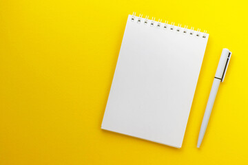 Blank notepad and pen on trendy dark yellow background. Notebook for ideas message, list and inspiration. Top view, flat lay with copy space. Mockup for your design.