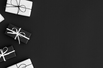 Black and white christmas gifts on a black background. Flat lay with blank copy space.