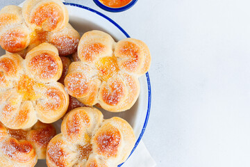 Beautiful yeast buns in the shape of flowers in an enameled bowl, top view, copy space