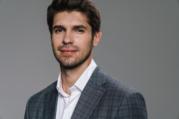 Photo of pleased businessman in jacket posing and smiling at camera