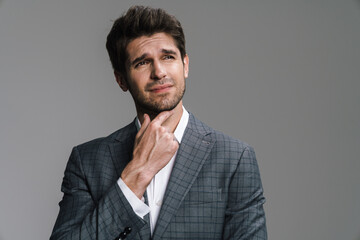 Photo of perplexed young businessman in jacket posing and looking aside