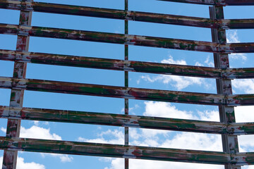 Colorful metal slats with blue sky and clouds in the background