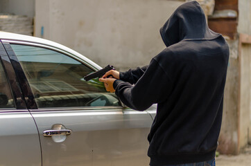 Terrorist or a car thief pointing a gun at the driver - car owner - obrazy, fototapety, plakaty