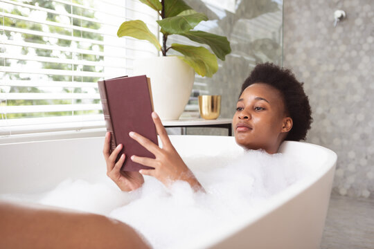 Woman reading book in a bathtub