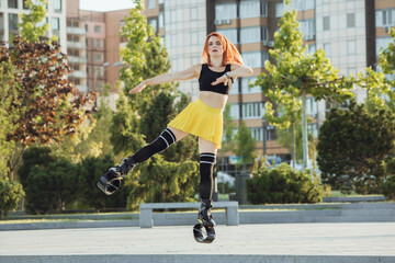 Beautiful woman in sportswear jumping in a kangoo jumps shoes at the street on summer's sunny day. Jumping high, active movement, action, fitness and wellness. Fit female model during training.