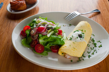 Omelette. Classic traditional american brunch/breakfast menu item served at traditional american restaurant. Farm fresh eggs, cooked in butter with fresh vegetables pork/bacon and served with salad 