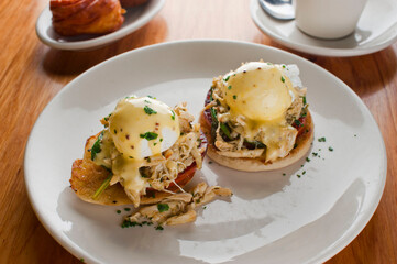 Eggs Benedict. Poached eggs w/ potato hash served in a cast iron skillet. English muffin. eggs, country ham, melted cheese, & homemade hollandaise sauce. Classic French or American cuisine favorite.