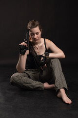 Obraz premium the Girl sits on the floor and leans her forehead against the barrel of the gun