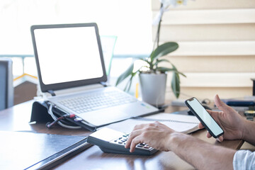 Close Up of man hands using mobile phone and laptop computer with blank copy space screen for your advertising text message or content business at a office shop with a document.