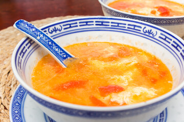Bowl of traditional chinese tomato soup with fresh tomatoes and egg