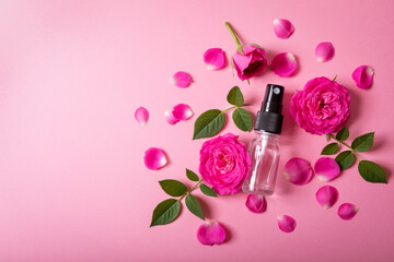 rose water spray with pink fresh flowers and petals on pink background with copy space