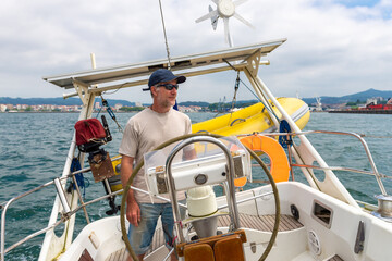 sailor steering sailboat, smiling happy man, sunny day
