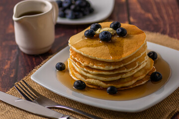 Pancakes servidos con moras azules, mantequilla y jarabe de maple listo para comer en la mañana