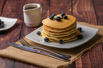 6 medium pancake tower with blueberries toppings and maple syrup ready for breakfast time.