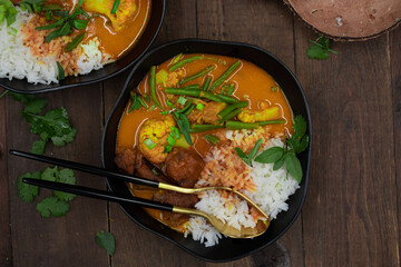 Vegan Thai red curry with seitan, beans and cauliflower over rice, served in black bowls