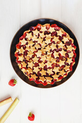 Strawberry and rhubarb pie decorated with stars on white table, top view