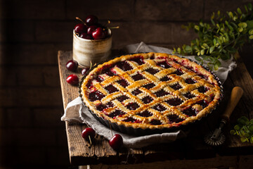 Delicious homemade classic cherry pie with a flaky crust on dark rustic background © petrrgoskov