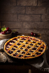 Delicious homemade classic cherry pie with a flaky crust on dark rustic background